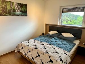 a bedroom with a bed with blue comforter and a window at Forellenwirt Bacher in Kirchberg