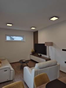a living room with white furniture and a flat screen tv at Villa Freska in Rogaška Slatina