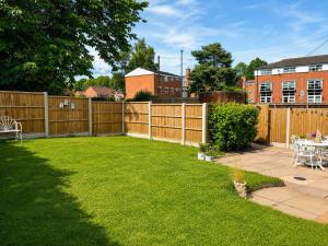 a backyard with a wooden fence and a lawn at Nightingale Cottage in Stafford