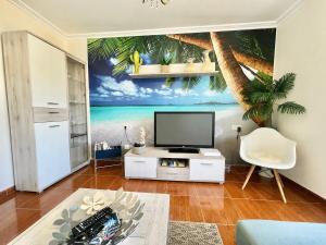 a living room with a tv and a palm tree mural at Casa baja a la playa in Bueu