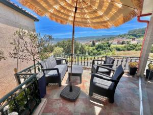 a patio with chairs and a table and an umbrella at Casa baja a la playa in Bueu