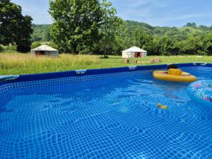 a large swimming pool with a yellow raft in a field at Les Cabanes d Erhes in Saint-Pé-de-Bigorre