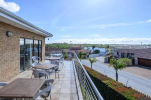 a balcony with a wooden table and chairs on a building at Diamond Style Guesthouse in Gqeberha