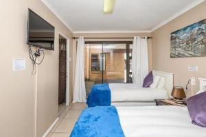 a hotel room with two beds and a flat screen tv at Diamond Style Guesthouse in Gqeberha