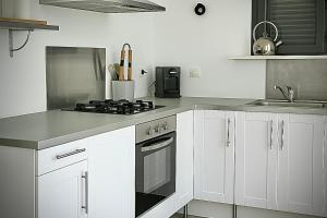 a kitchen with white cabinets and a stove top oven at l'Alzelle Plage in Biguglia