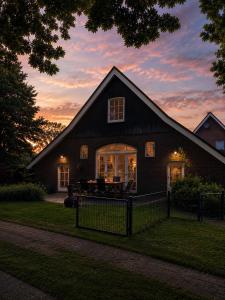 a barn house with a sunset in the background at Huize Kroezzz sfeervolle authentieke vakantie woning met 3 slaapkamers, omheinde tuin en honden welkom in Goor