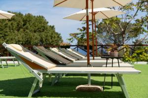 a row of lounge chairs with umbrellas on the grass at Pater Meus Suites - Sea View, Pool & Parking in Cefalù