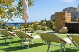 a group of lawn chairs and an umbrella at Pater Meus Suites - Sea View, Pool & Parking in Cefalù
