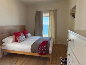 a bedroom with a bed with red pillows and a window at B&B Tre Finestre sul Mare in Grottammare