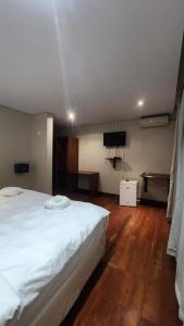 a bedroom with a white bed and a flat screen tv at ORO - Boutique Guesthouse in Matola