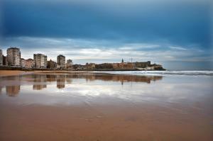 vistas a una playa con edificios y al océano en Hotel Avenida, en Gijón