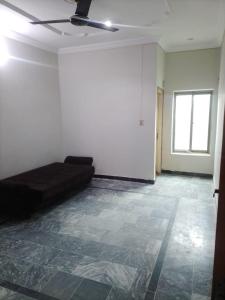 an empty room with a couch and a window at Spacious 2 Bed Room Home Attached Baths, Lounge & Kitchen in Abbottabad +2 photos