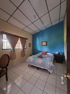 a bedroom with a bed and a blue wall at GuacamayaGuestHouse in Concepción de Ataco