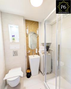 a white bathroom with a toilet and a sink at P6 Lipowa in Pisz