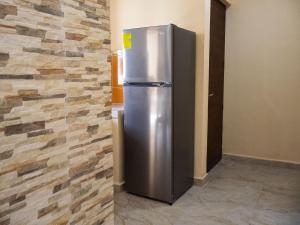 a stainless steel refrigerator in a room with a stone wall at Jardín del Mar by ÓOL Hotels in Holbox Island