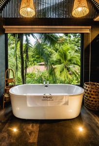 a bath tub in a room with a large window at Namu Garden Hotel & Spa - Adults Only in Puerto Viejo