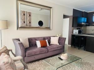 a living room with a purple couch and a mirror at CLASSY and COZY 3 in Fourways +27 photos