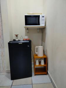 a microwave sitting on a shelf above a refrigerator at Pernoitar in São José