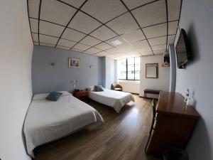ein Zimmer mit zwei Betten und einem Fernseher in der Unterkunft Hotel Italia Cuenca - Tranvia Centro & Aeropuerto in Cuenca + 38 Fotos