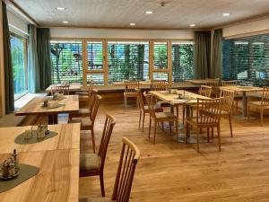 a restaurant with wooden tables and chairs and windows at Haus der Achtsamkeit in Grünau im Almtal
