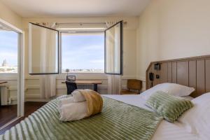 ein Schlafzimmer mit einem Bett und einem großen Fenster in der Unterkunft Logis Hôtel Rêve de Sable in Royan