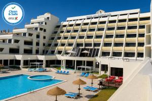 a hotel with a pool and chairs and umbrellas at Hotel Atlantida Sol in Figueira da Foz