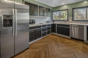a kitchen with stainless steel appliances and wood floors at Camp Smores- Modern A-Frame with Pool in Newfield