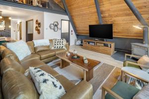 a living room with leather furniture and a flat screen tv at Camp Smores- Modern A-Frame with Pool in Newfield