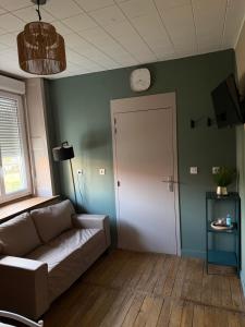 a living room with a couch and a clock on the wall at Le pensionnat de Jeanne in Domrémy-la-Pucelle