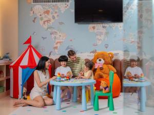 a family sitting at a table with a teddy bear at Mercure Bangkok Sukhumvit 11 in Bangkok