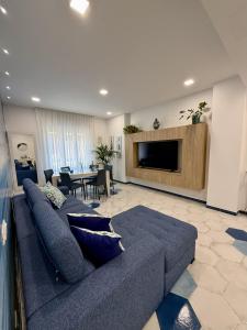 a living room with a blue couch and a tv at Capri House - camera Luna Caprese in Minori