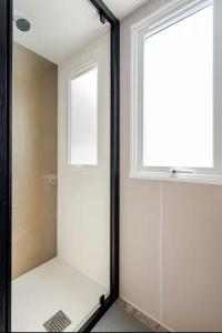 a glass shower door with a window in a bathroom at Le petit paradis du golfe in Gassin