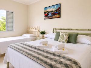 a white bedroom with two beds and a window at Pousada Casa Contos de Minas in Ubatuba