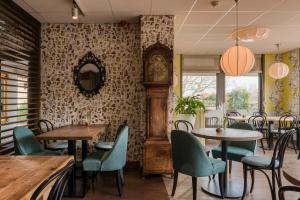 a restaurant with tables and chairs and a grandfather clock at Hotel Op Diek in Den Hoorn