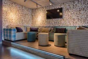 a living room with a couch and a tv on a wall at Hotel Op Diek in Den Hoorn