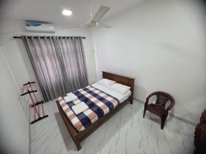 a bedroom with a bed and a chair and a window at Villa at 37 in Badulla