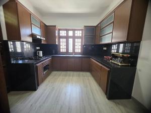 a large kitchen with black counters and wooden cabinets at Villa at 37 in Badulla