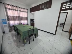 a dining room with a green table and chairs at Villa at 37 in Badulla +2 photos