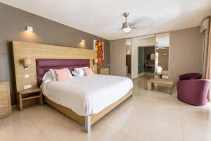 a bedroom with a large bed and a purple chair at Villa Ellia - Terres Basses in Les Terres Basses +6 photos