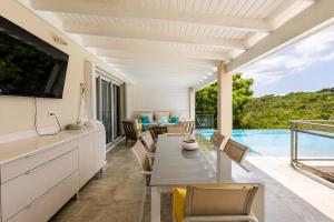 a kitchen and dining room with a view of a pool at Villa Ellia - Terres Basses in Les Terres Basses