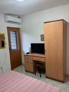 a bedroom with a desk with a television and a cabinet at Vila Maša in Utjeha
