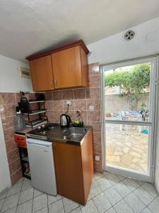 a kitchen with a sink and a stove and a window at Vila Maša in Utjeha