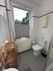 a white bathroom with a toilet and a window at Ferienwohnung Waldblick in Harrislee +4 photos