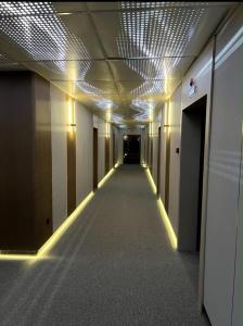 a hallway in an office building with lights on the ceiling at Raduga West Apart Hotel in Koshkolʼ
