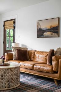 a brown leather couch in a living room with a table at Black Mountain Bungalow Steps to Town Backyard in Black Mountain +24 photos
