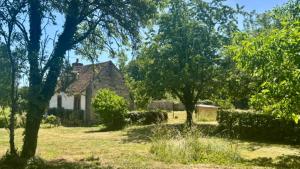 an old house in the middle of a field with trees at À la Pays Anes in Tannerre-en-Puisaye