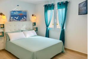 a bedroom with a white bed with blue curtains at Arthouse Sea View - Acquamarina e Zaffiro in Puerto del Carmen
