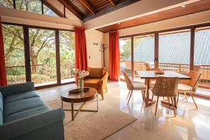 a living room with a table and chairs and windows at Green Forest Rustic Houses in Monteverde Costa Rica