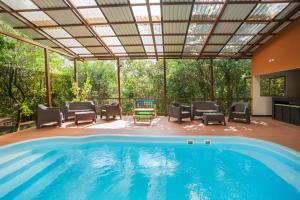 an indoor swimming pool with a patio with chairs and a table at Green Forest Rustic Houses in Monteverde Costa Rica