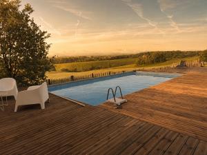 a swimming pool with two white chairs on a wooden deck at GiteLaGrange in Lalanne-Arqué